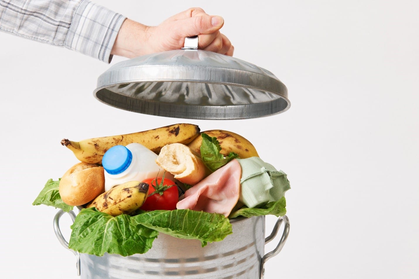A trashcan full of still edible food with a man holding open the lid