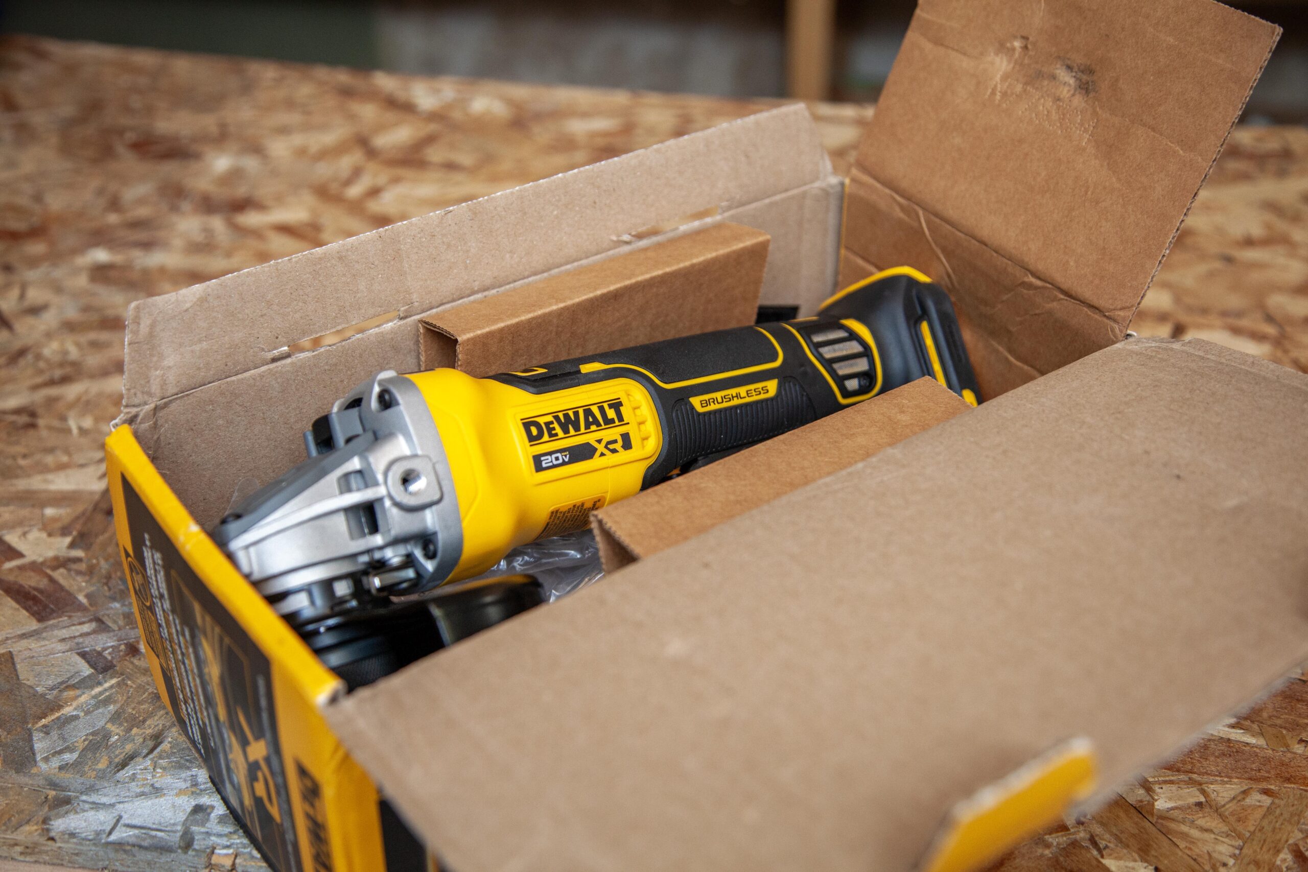Dewalt 20V brushless cordless tool displayed in an open box on a wooden surface, showcasing the product's packaging and design features.