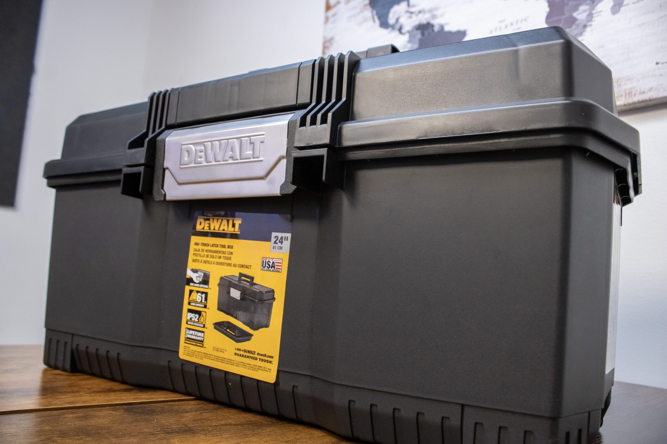Black tool box with 24-inch capacity, featuring brand logo, on a wooden surface. Suitable for heavy-duty storage.