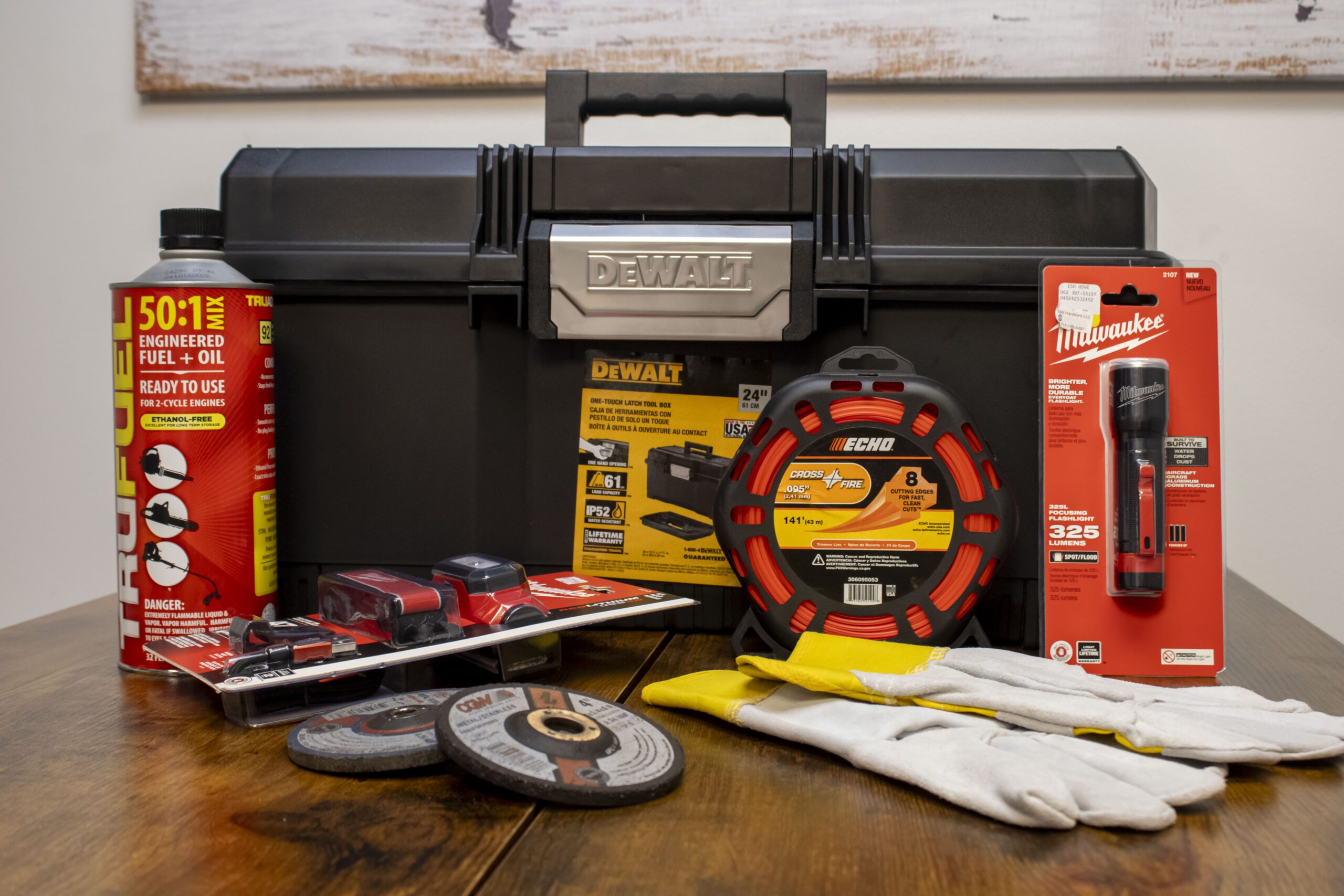 Toolbox set with various tools and accessories including flashlight, gloves, and fuel mix on a wooden table.