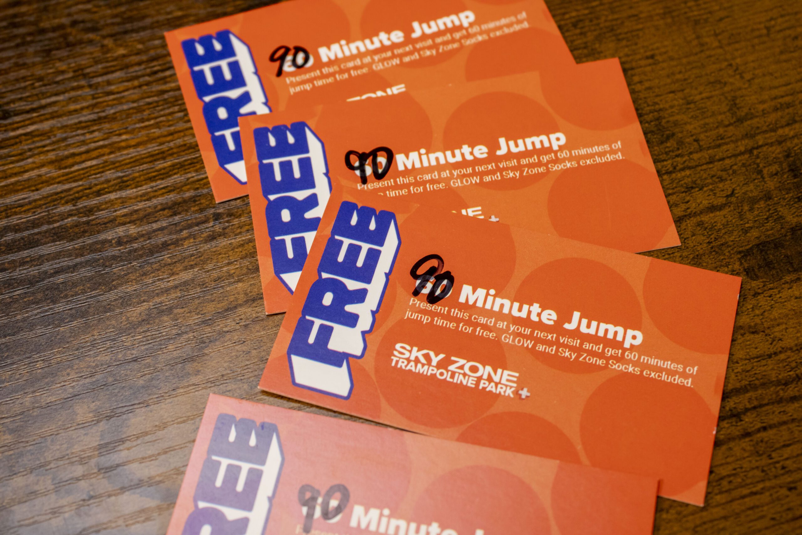 Free 90-minute jump passes for Sky Zone Trampoline Park displayed on a wooden surface, featuring details on redeeming the jump time.