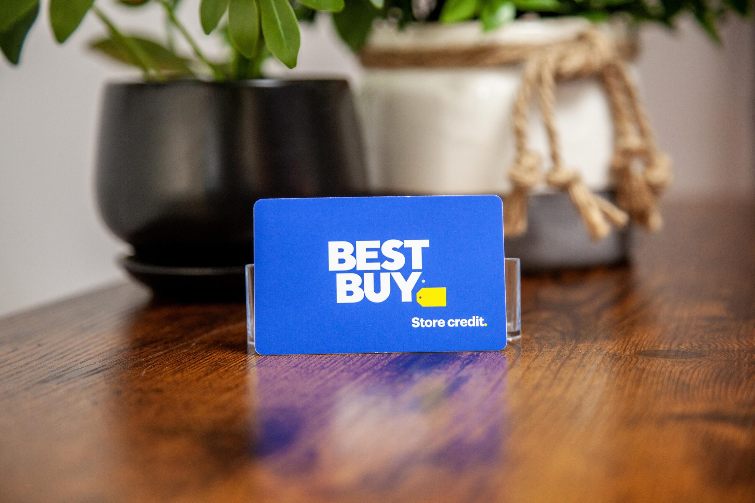 Best Buy store credit card on wooden table with potted plants in background for a modern retail setup.