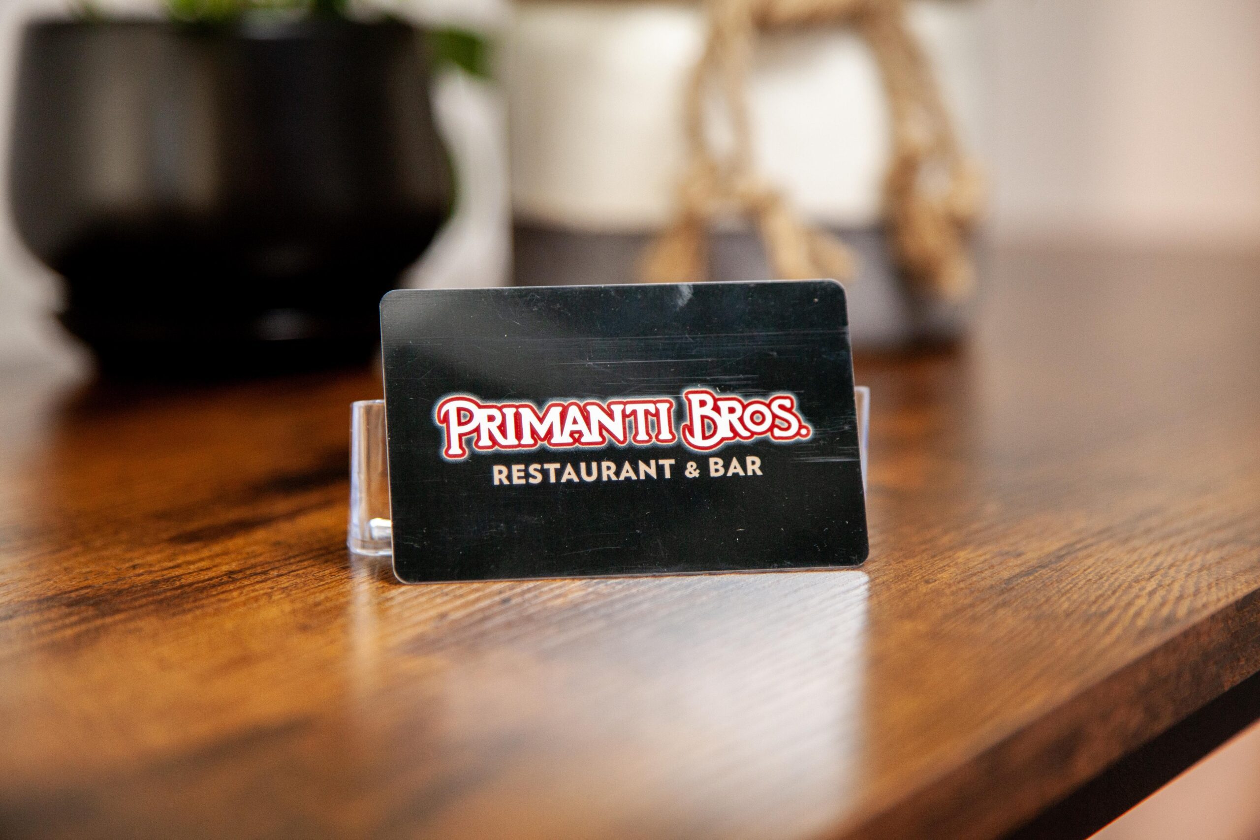 Primanti Bros. restaurant and bar gift card displayed on a wooden table, showcasing the brand's logo and name prominently.