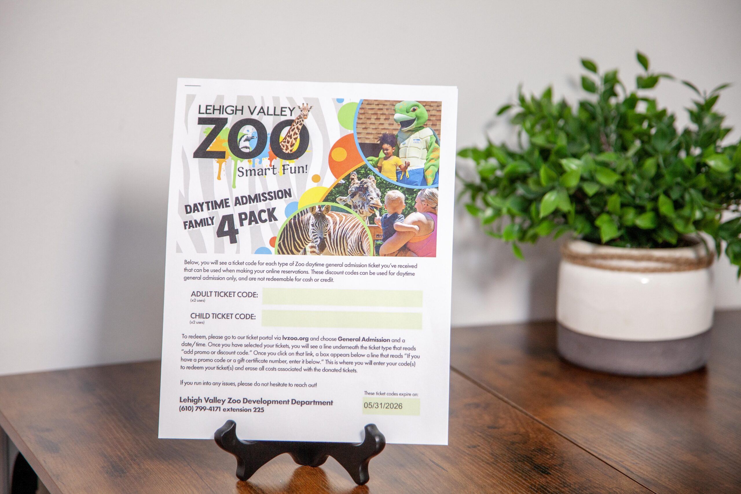 Flyer for Lehigh Valley Zoo family admission pack on wooden table with plant.