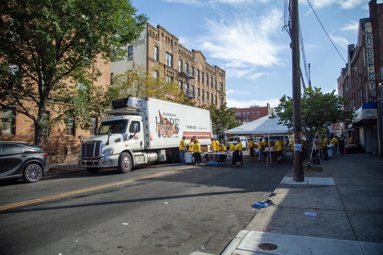 Truck with Blessings of Hope logo at an outdoor event with volunteers in yellow shirts under a tent.
