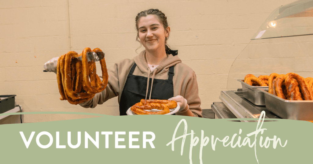 Smiling young volunteer in an apron serving freshly made pastries at a community event, highlighting volunteer appreciation efforts.