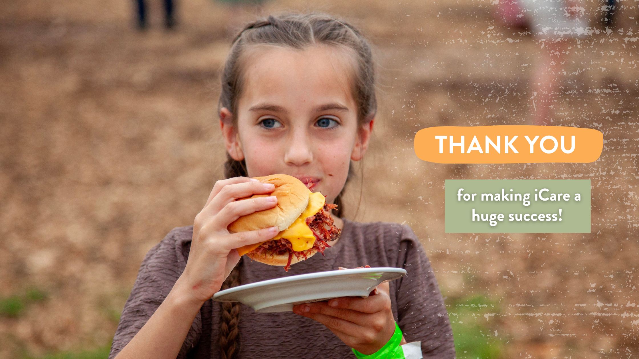 Young girl enjoying a delicious hamburger at an outdoor event, showcasing a spirit of gratitude for the success of the iCare initiative.