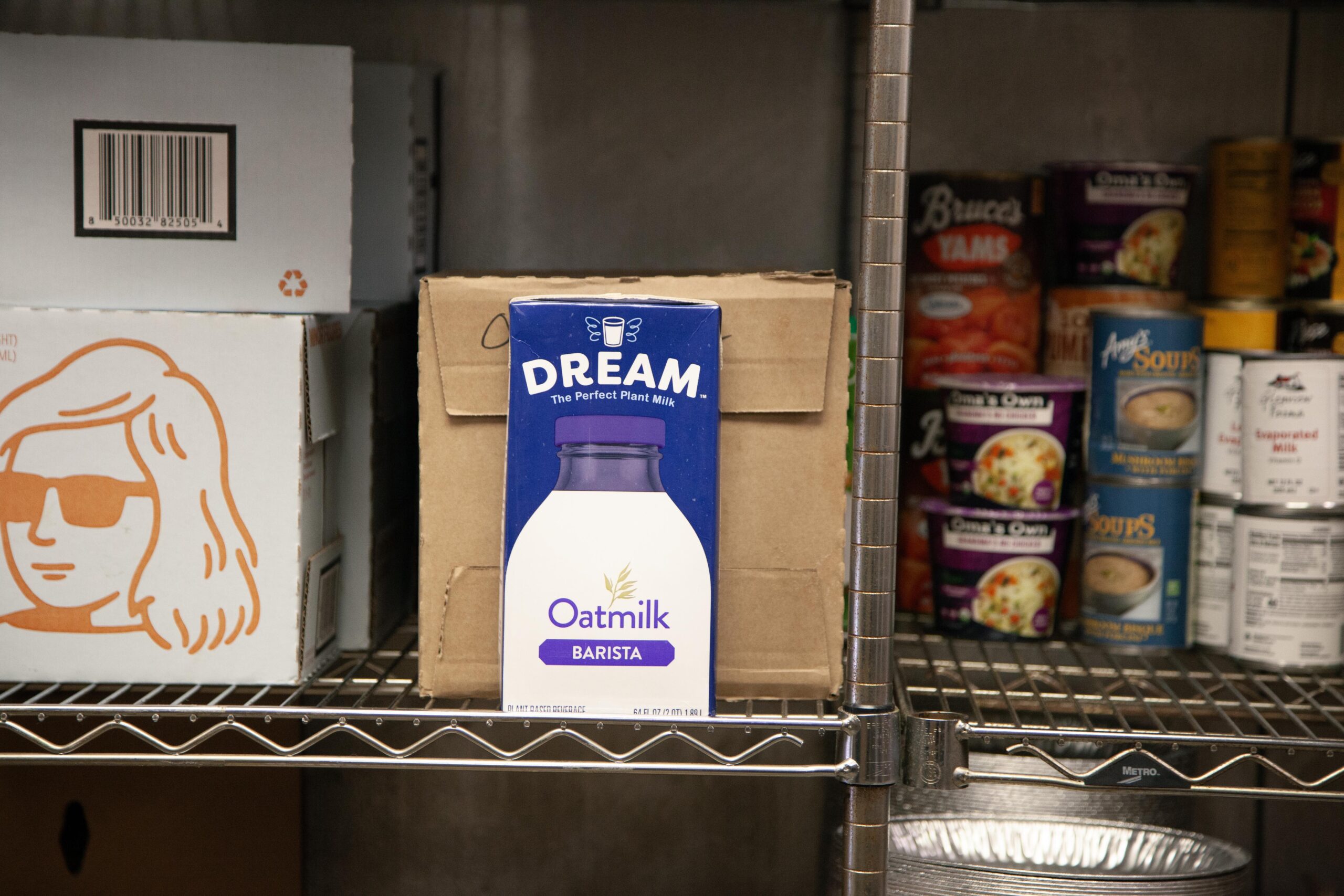 Oatmilk Barista by Dream displayed on a shelf, surrounded by various food items and packaging, highlighting plant-based milk options for coffee and beverages.