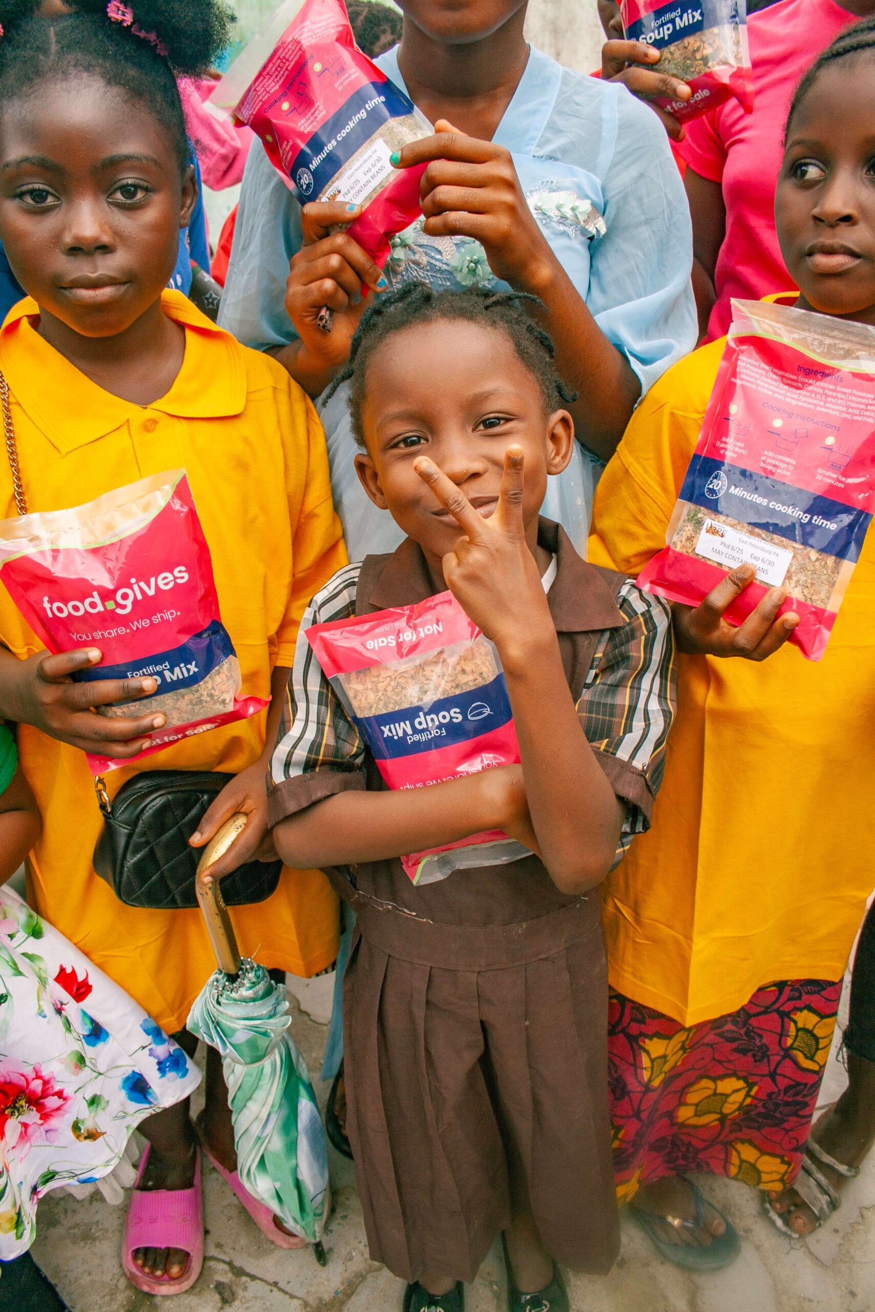 Children holding food packages from a community support initiative, showcasing smiles and a sense of joy. The image highlights the importance of food distribution programs in aiding local families.