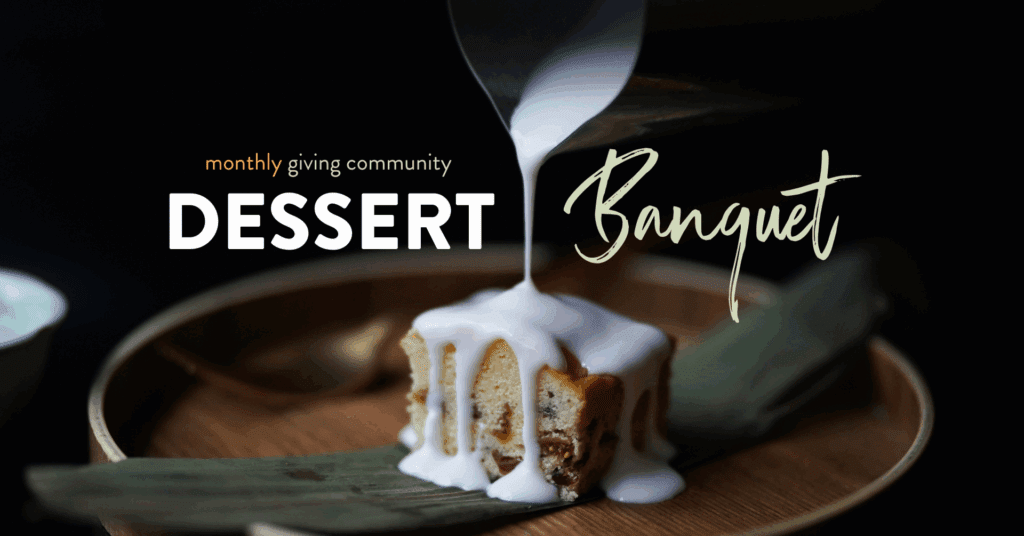 Dessert banquet featuring a slice of cake topped with a creamy glaze, presented on a wooden plate with bamboo leaves, promoting a monthly giving community event.