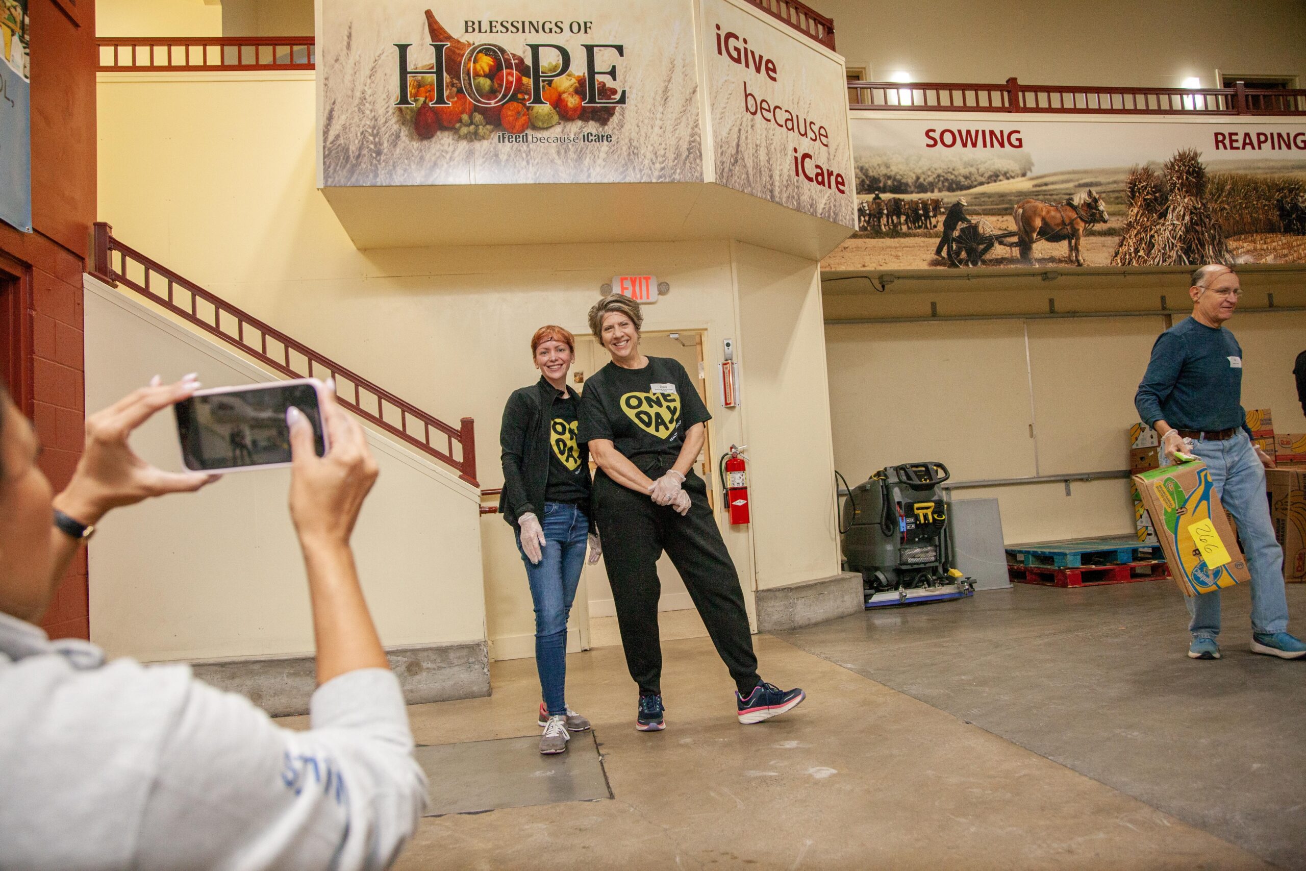 Volunteers at Blessings of Hope smiling and posing for a photo while participating in a community service event, with banners promoting giving and care in the background.