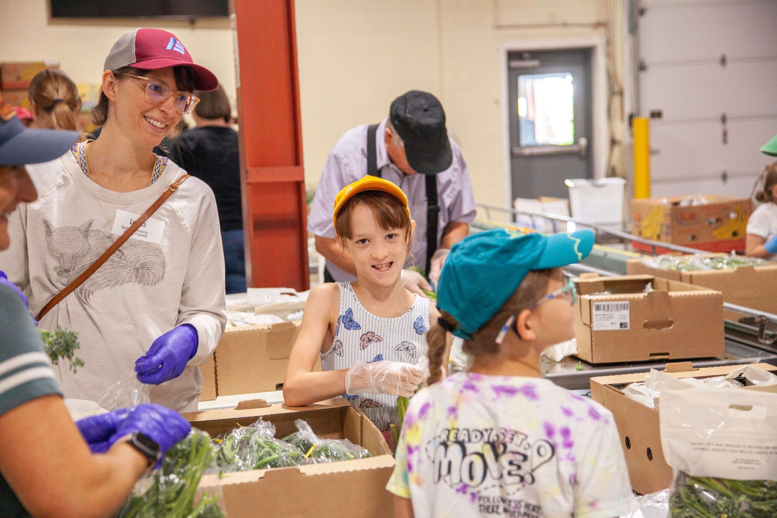 Volunteers sorting fresh produce at a community food distribution center, engaging children in food preparation and teamwork activities.
