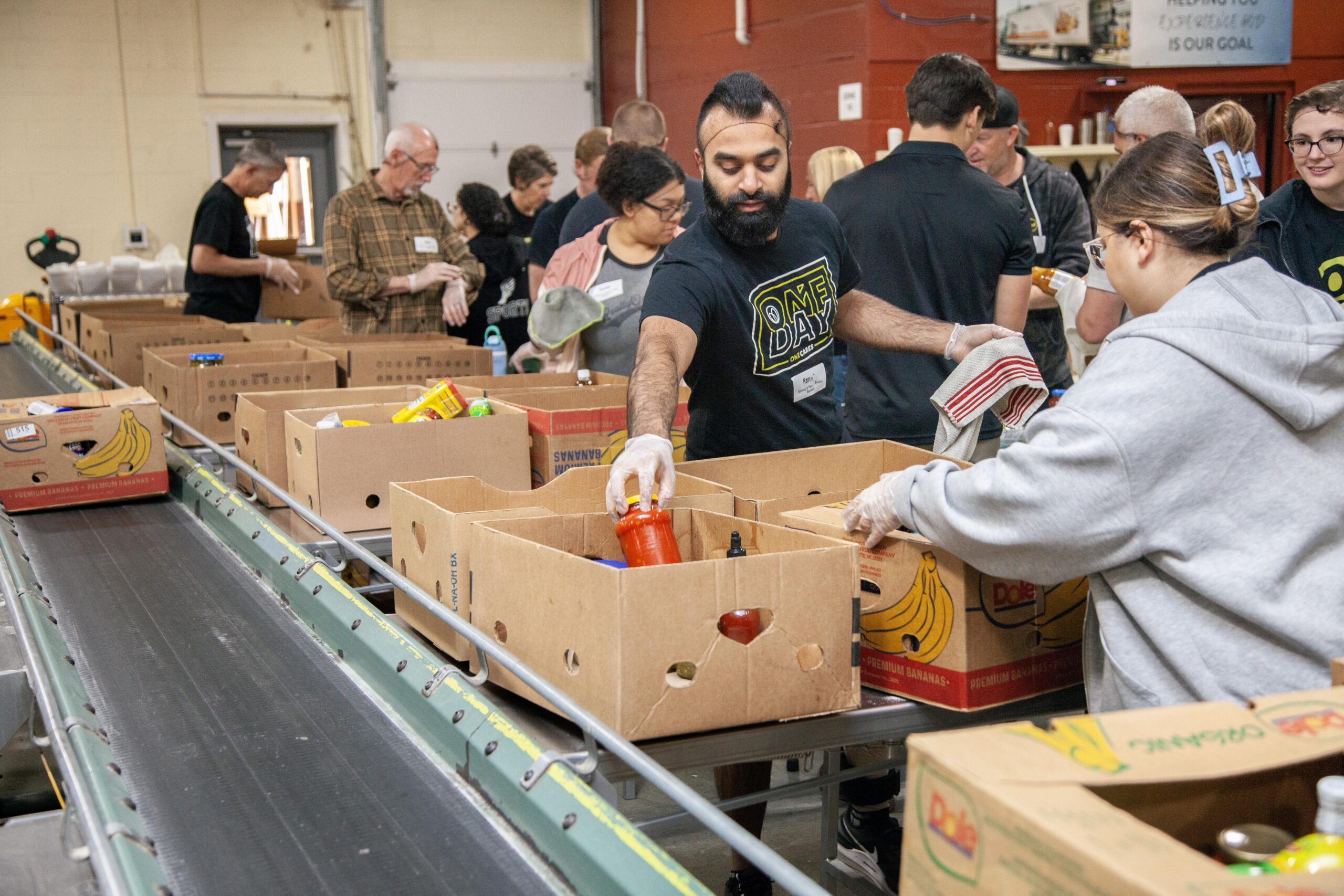 Volunteers sorting food items into cardboard boxes at a food bank, promoting community service and food distribution efforts.