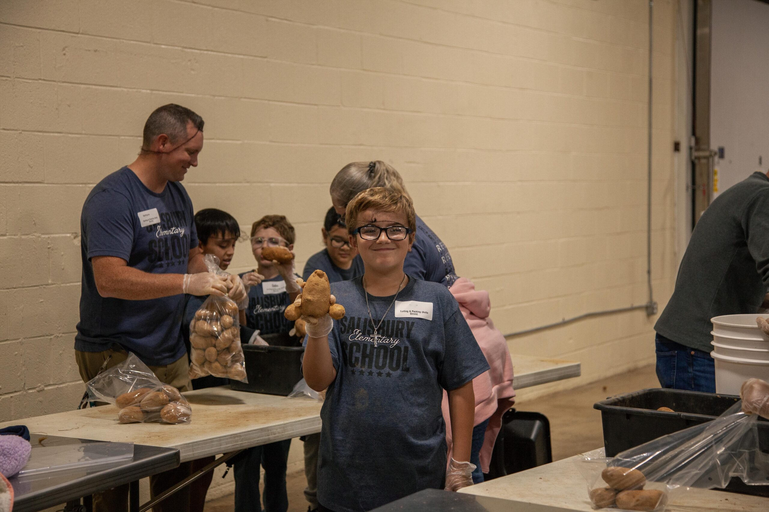 Children volunteering at Salisbury Elementary School, sorting and packaging sweet potatoes in a community service event.