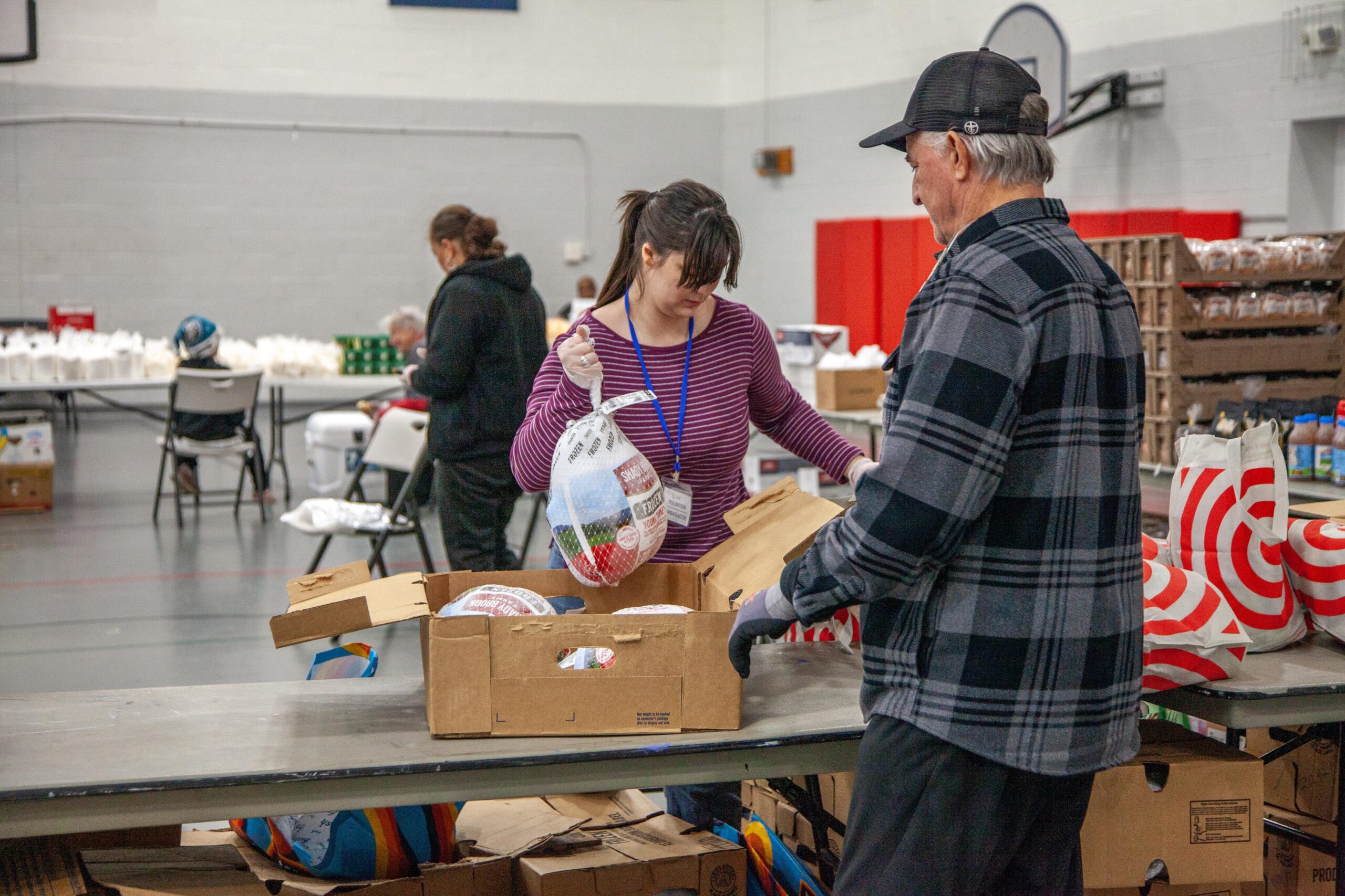 Volunteers sorting and distributing turkeys at a community food bank event, with a focus on providing meals to those in need during the holiday season.