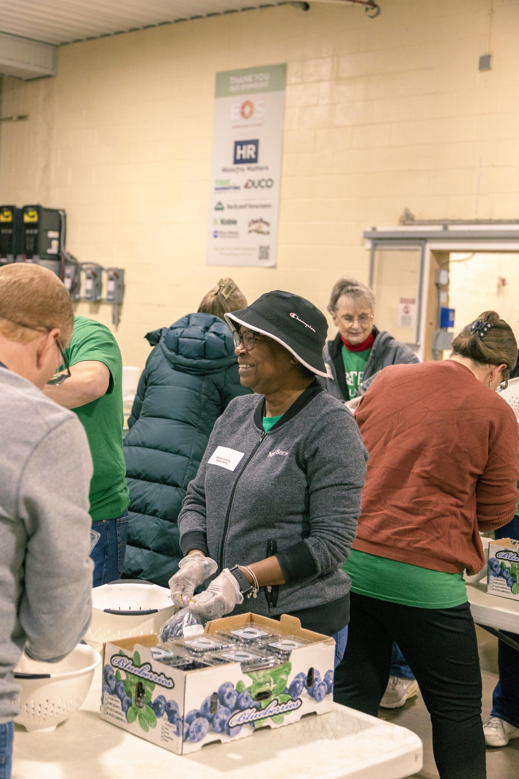 Volunteers sorting and distributing blueberries at a community food event, showcasing teamwork and engagement in a supportive environment.