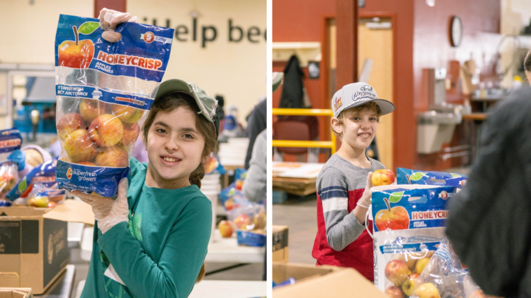 Children volunteering at a food distribution center hold bags of Honeycrisp apples, showcasing their involvement in community service and healthy food initiatives.