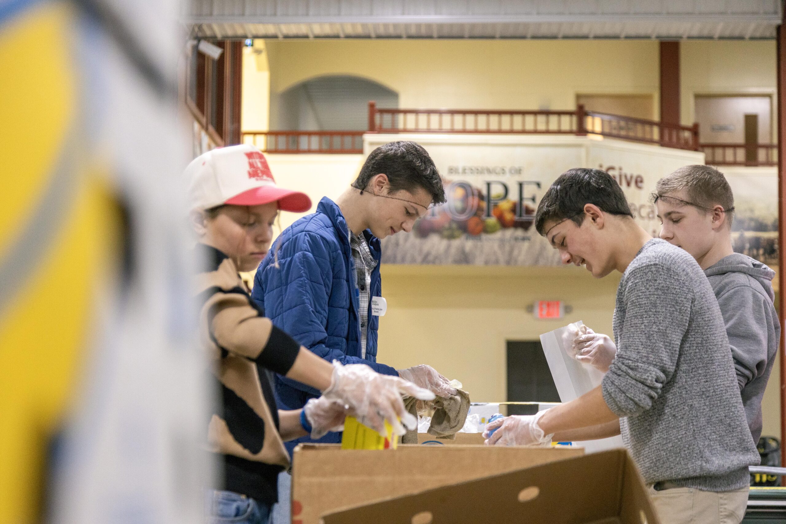 Volunteers participating in a food packing event, sorting and organizing items into boxes at a community center, promoting teamwork and service.