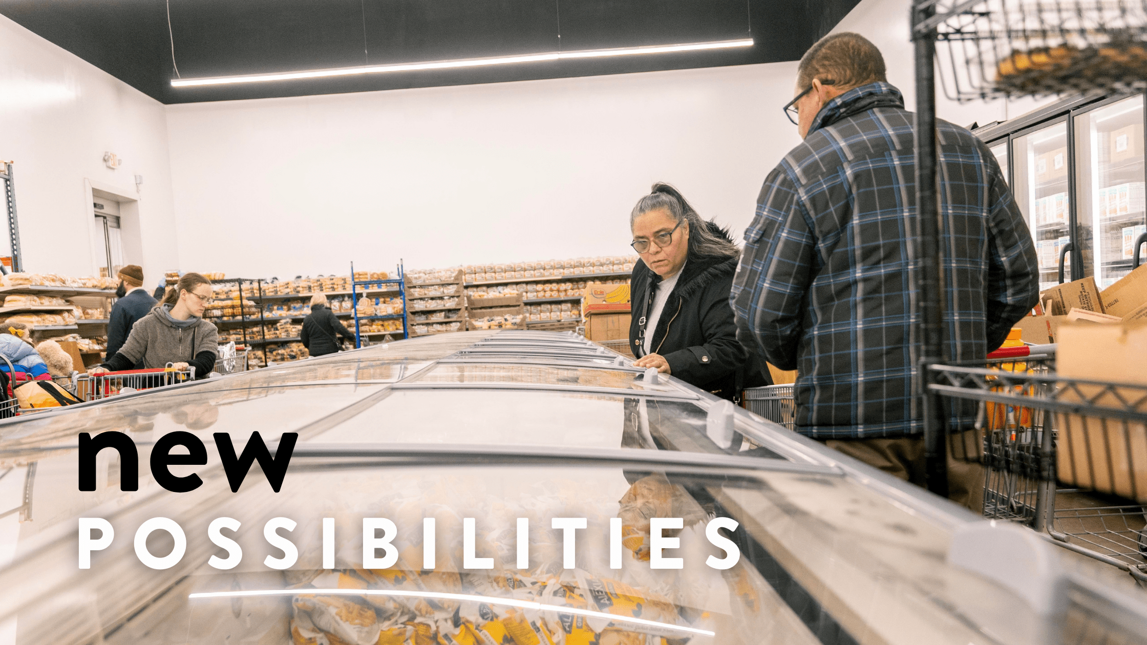 A diverse group of shoppers explores a grocery store aisle filled with various baked goods while examining items in a refrigerated display case. The image conveys themes of community and accessibility in food shopping.